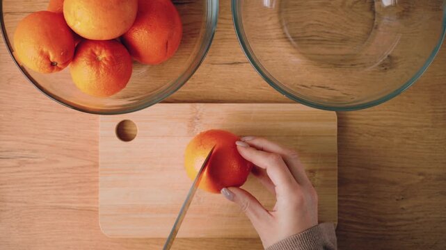 Preparing fresh orange juice in a home kitchen as part of a healthy morning. Female hands cut oranges . Calm lifestyle, natural nutrition, simple home routine.