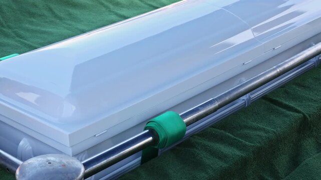 Coffin is resting on green cloth in cemetery setting during burial ceremony