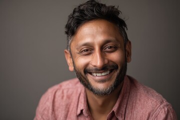 Obraz premium Direct gaze: cheerful Indian man portrait with soft lighting and neutral background