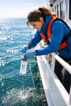 Young woman conducting water sampling on a boat at sea