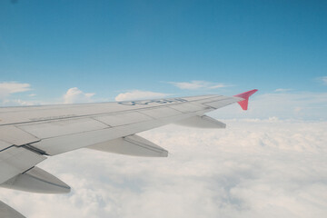 Obraz premium Airplane wing view above clouds with clear blue sky