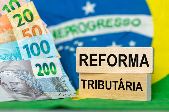 Tax reform, words written in Brazilian Portuguese on wooden blocks against the backdrop of the Brazilian flag and money. Financial Concept, Taxes in Brazil