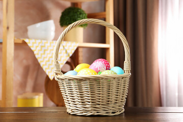 Fototapeta premium Easter basket with painted eggs on wooden table indoors