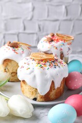 Delicious Easter cakes, tulips and painted eggs on white marble table, closeup