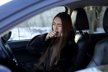 Naklejka premium Young woman feeling fatigue in her modern car, view from outside