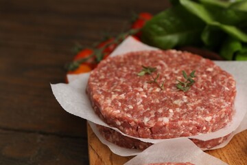 Uncooked meat patty with thyme, lettuce and tomatoes on table, closeup. Space for text