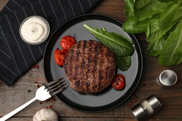 Obraz premium Delicious grilled meat patty, tomatoes and spinach on wooden table, flat lay