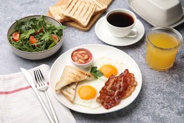 Traditional English breakfast. Delicious sunny side up eggs with bacon served on grey table, closeup