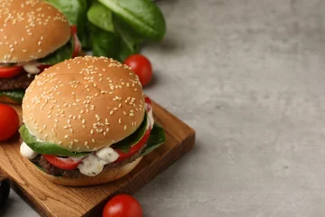 Fotobehang Eten Delicious burgers with meat patties on grey table, closeup. Space for text  © New Africa