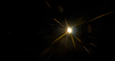 Fototapeta premium Abstract cinematic lens flare with bright light burst and star rays, isolated on black background. Optical light effect ideal for VFX overlays, transitions, titles and dramatic visual accents.