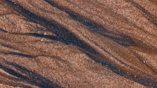 Magical with Black Sand Beaches on multicolored Hormuz Island, Iran. The dark sand from heavy minerals such as hematite, ilmenite, and magnetite, creating striking textures along the shoreline.