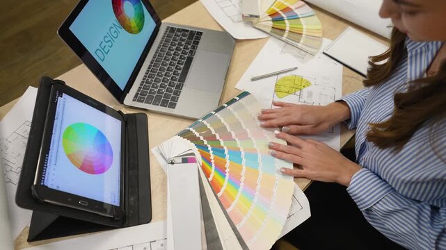 Designer choosing colors from swatch book at her desk
