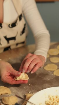 Woman placing filling on dumpling wrapper close-up