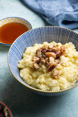 Delicious healthy breakfast: millet porridge cooked with coconut milk and toped up with caramelised mixed nuts and maple syrup