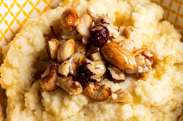 Delicious healthy breakfast: millet porridge cooked with coconut milk and toped up with caramelised mixed nuts and maple syrup