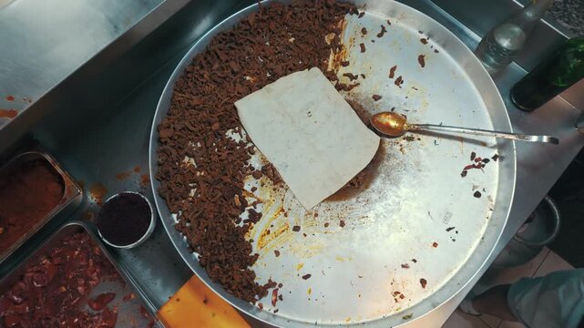 Traditional Turkish Street Food Tantuni: Chef Greasing Flatbread on a Large Metal Pan with Fried Meat