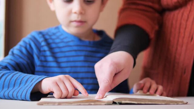 Teacher pointing to text in a book while a child student follows along