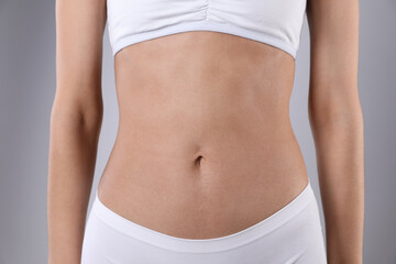 Woman in underwear after weight loss on grey background, closeup