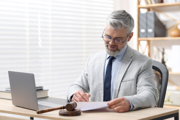 Fototapeta premium Notary in glasses and suit doing paperwork at table in office