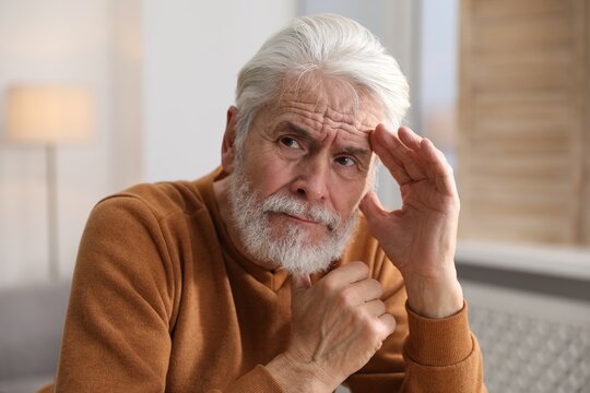 Amnesia. Senior man trying to remember something at home