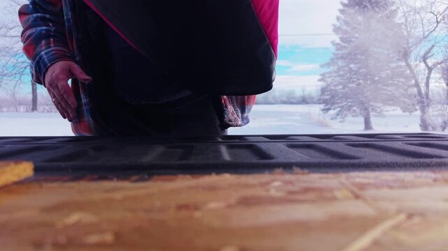 Man loading a bag into the back of a truck in winter