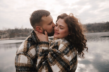 Fototapeta premium Couple shares a romantic moment outdoors on a cloudy day near a lake