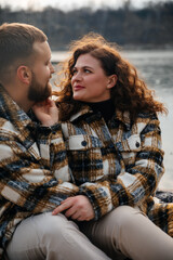 Fototapeta premium Couple sharing love on Valentines Day by the river in cozy outfits while enjoying their time together
