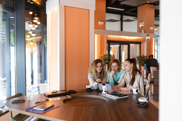 Business meeting among three women in a modern office environment, discussing strategies at a round...