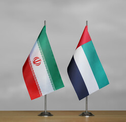 Two table flags of Iran and Emirates on a blurred gray background