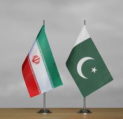 Two table flags of Iran and Pakistan on a blurred gray background