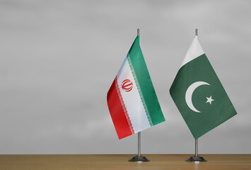 Two table flags of Iran and Pakistan on a blurred gray background