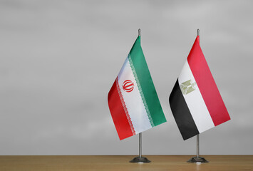 Two table flags of Iran and Egypt on a blurred gray background