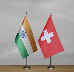 Two table flags of India and Switzerland on a blurred gray background
