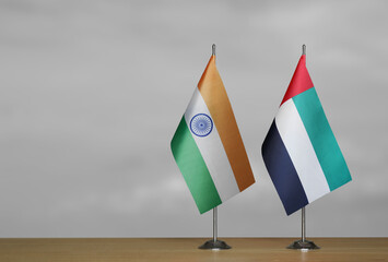 Two table flags of India and Emirates on a blurred gray background
