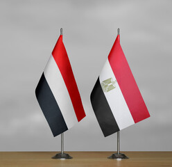 Two table flags of Yemen and Egypt on a blurred gray background