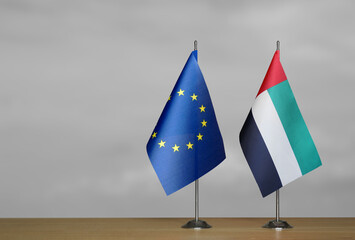 Two table flags of the European Union and Emirates on a blurred gray background