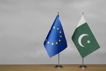 Two table flags of the European Union and Pakistan on a blurred gray background