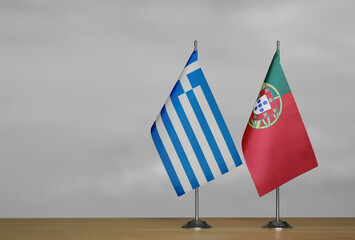 Two table flags of Greece and Portugal on a blurred gray background