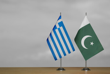 Two table flags of Greece and Pakistan on a blurred gray background