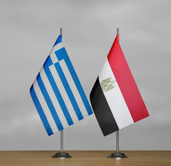 Two table flags of Greece and Egypt on a blurred gray background