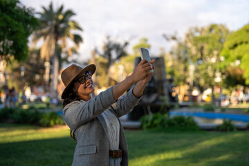 Woman smiling and taking a selfie with her phone in a city square in La Serena  © freechoice