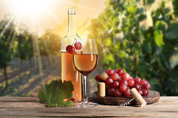 Naklejka premium Wine and fresh grapes on table. Glass and bottle in vineyard