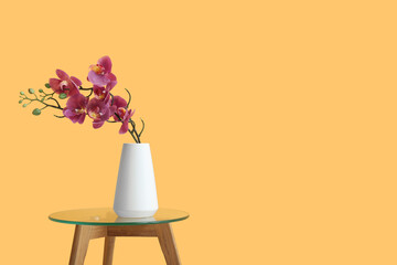 Vase with artificial orchid flower on table near orange wall © Pixel-Shot