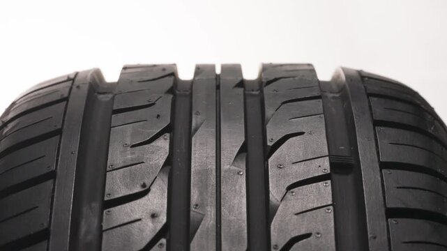 Buying New Car Tires. New car wheel close-up slowly spinning showing tread pattern on white background
