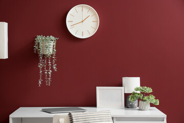 Modern workplace and clock on red wall in office