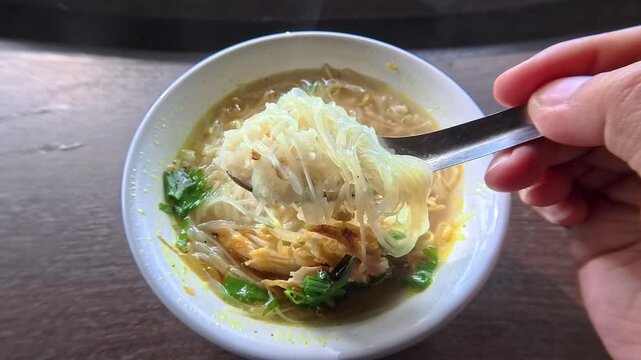Close Up Of Hand Scooping Hot Soto Soup With Steam Rising From Bowl