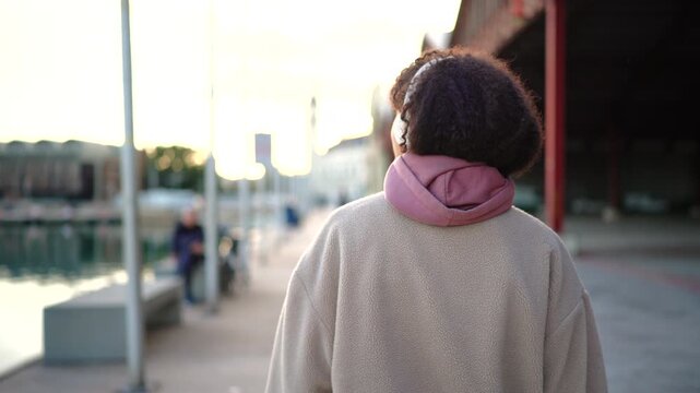 Woman walking along city path wearing headphones, relaxed breathing and smooth motion, urban fitness lifestyle, daily workout habit, motivation, wellness balance and control