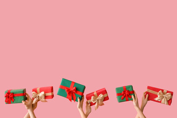 Naklejka premium Female hands holding Christmas gift boxes on pink background