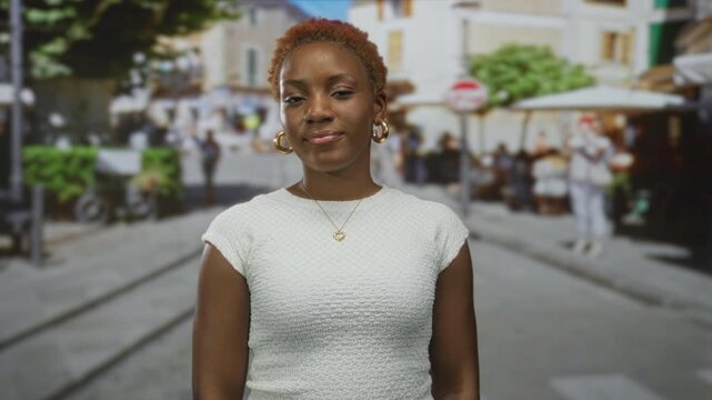 Young african american woman beckons with finger on sunlit street corner amid blurred pedestrians; invitation.