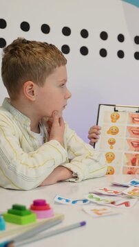 Young boy learning emotions with flashcards during therapy session